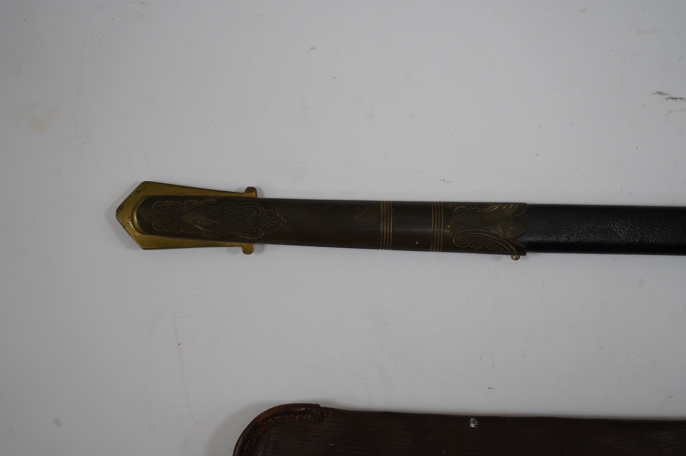 A George VI naval officer’s dress sword by Wilkinson (unnumbered), with regulation brass hilt with folding guard, engraved P.A.R. Gould R.N., bullion dress knot, in its brass mounted leather scabbard and contained in its